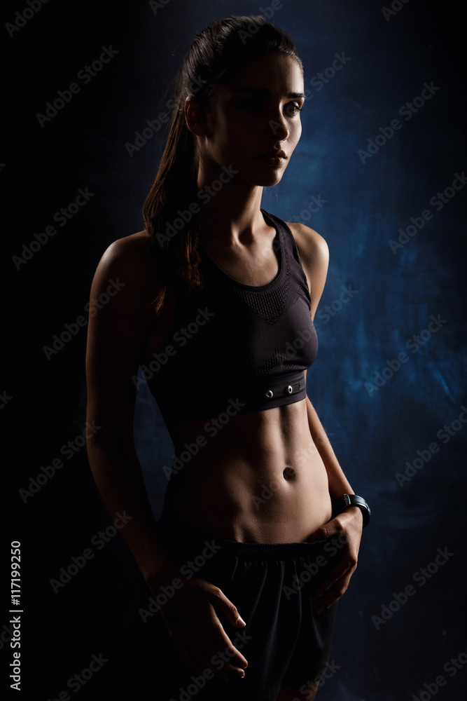 Young beautiful sportive girl posing over dark background. Copy space. Young beautiful sportive girl posing over dark background. Copy space.