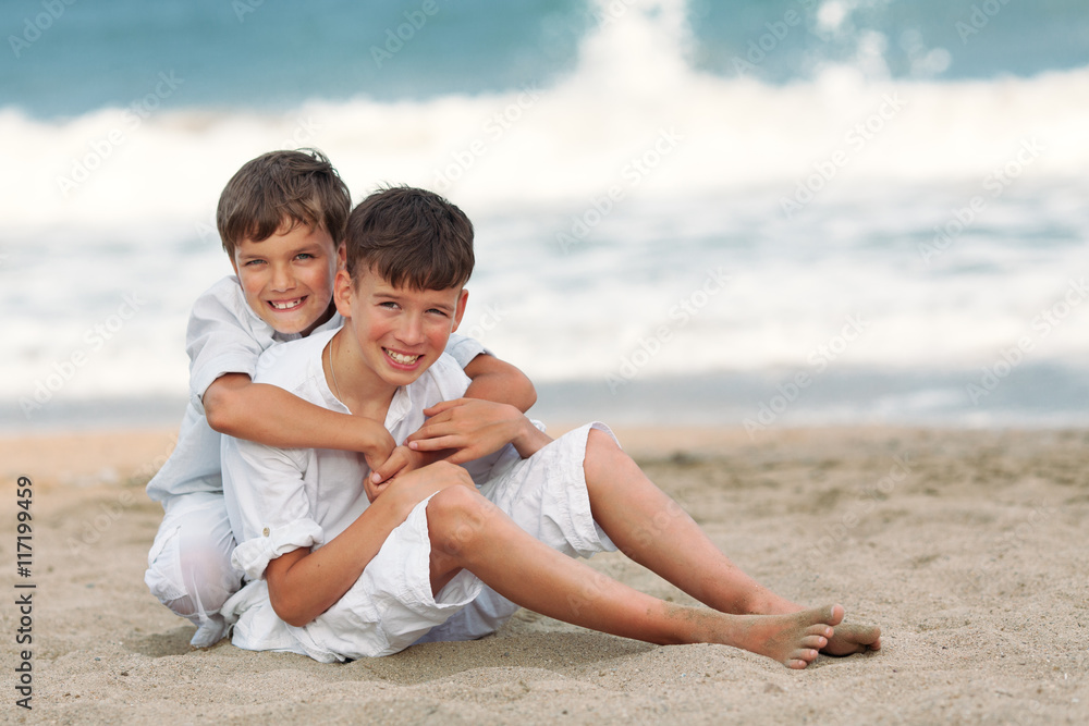 Portrait of happy brothers in white shirts on background of sea