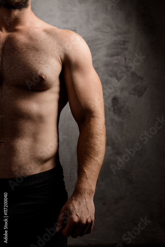 Close up of sportive man's body over dark background.