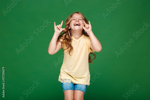 Young pretty girl laughing over green background.