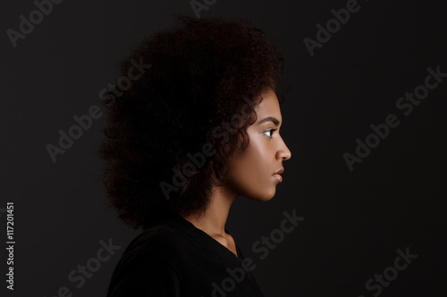 Portrait of young beautiful african girl  over dark background. © Cookie Studio