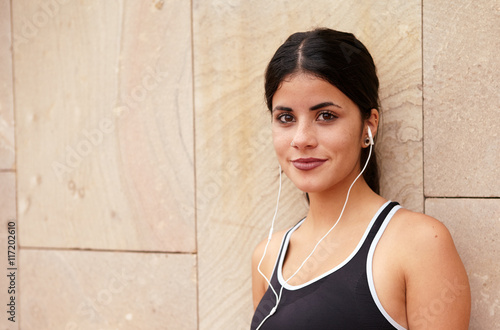 Obraz na plátně Young brunette with earphones and secretive smile