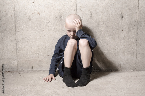 Neglected lonely child leaning at the wall