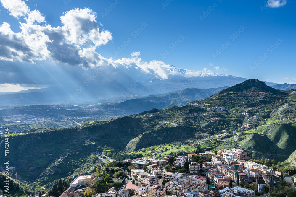 View of the Taormina city and the active volcano Etna in the sunlights. Province of Messina.Sicily. Italy.