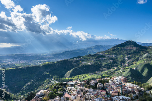 View of the Taormina city and the active volcano Etna in the sunlights. Province of Messina.Sicily. Italy. © serg_did