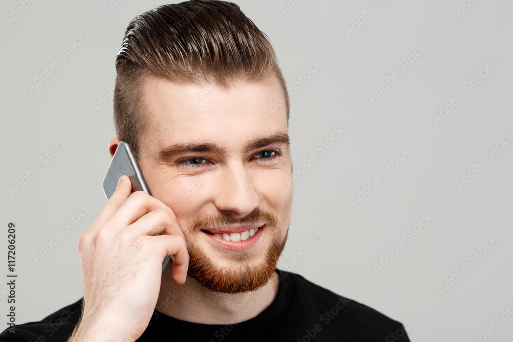Young handsome man speaking on phone over grey background. Young handsome man speaking on phone over grey background.