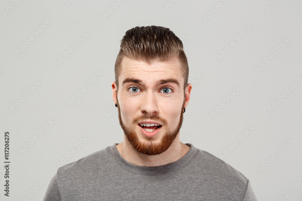 Fototapeta premium Surprised young handsome man posing over grey background. Copy space.