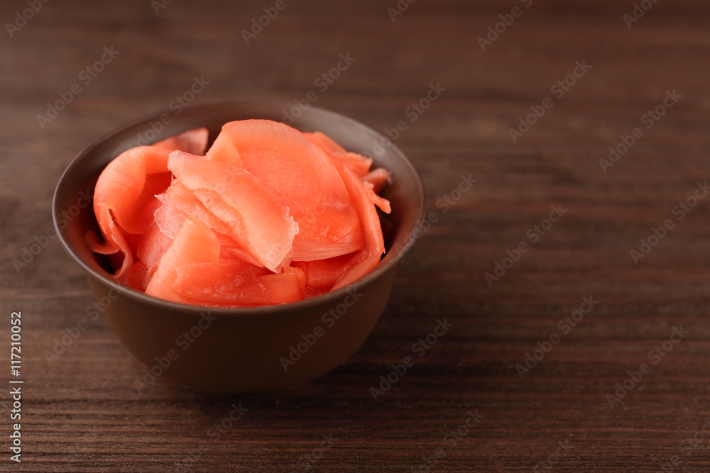 Bowl of marinated ginger on wooden background