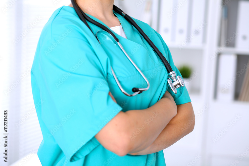Female surgeon doctor is standing with arms crossed at hospital. Physician is ready to examine patient Female surgeon doctor is standing with arms crossed at hospital. Physician is ready to examine patient