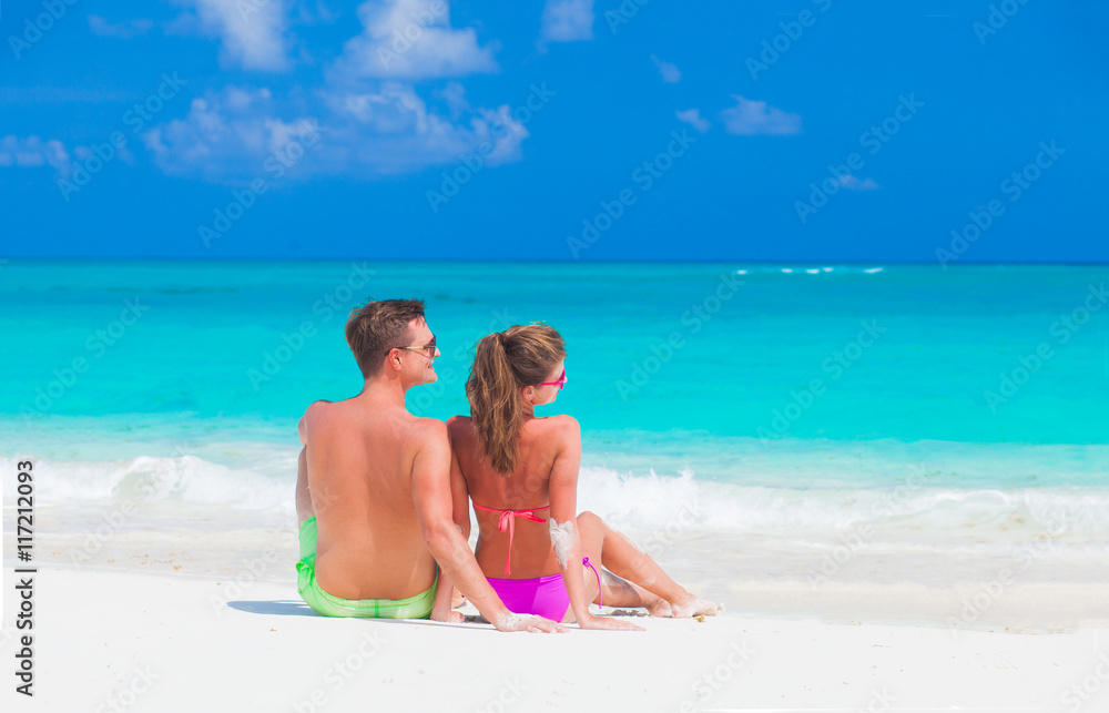back view of couple sitting on a tropical beach in CAyo Largo