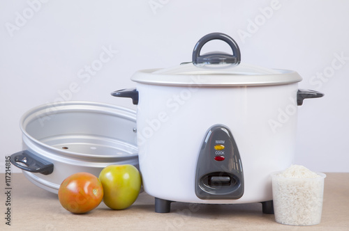 white rice cooker with accessory to cook steamed vegetables