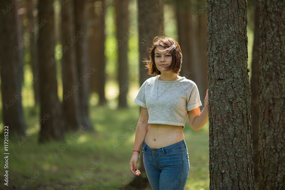 Teen girl standing in the woods near a tree. Teen girl standing in the woods near a tree.