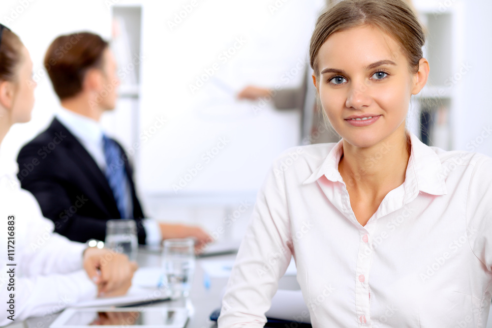 Portrait of a young business woman against a group of business people at meeting. Portrait of a young business woman against a group of business people at meeting.