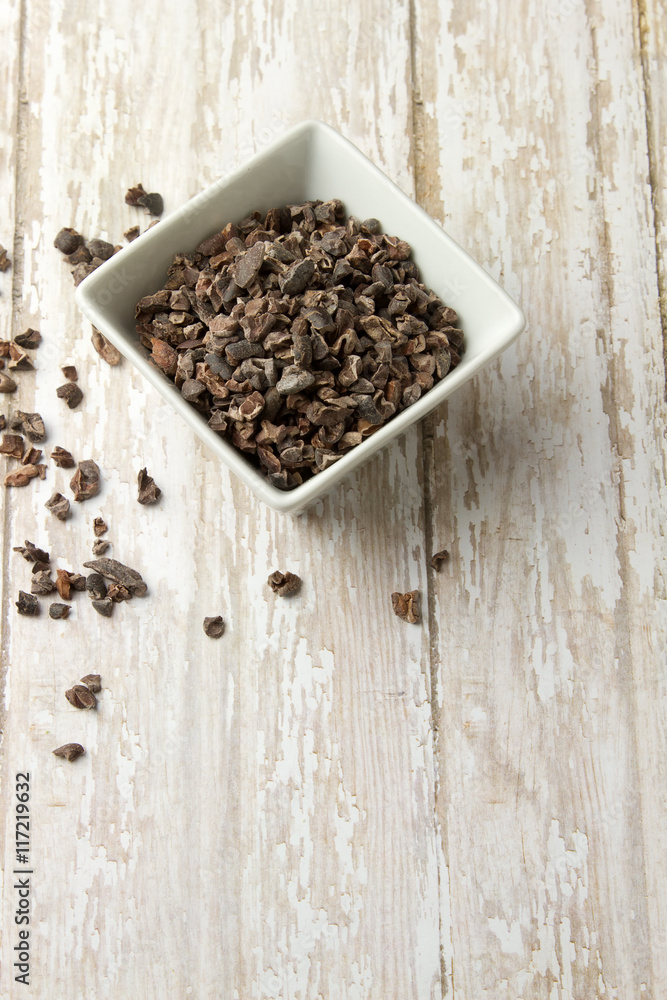 Bowl of Organic Cacao Nibs on a wood plank board Bowl of Organic Cacao Nibs on a wood plank board
