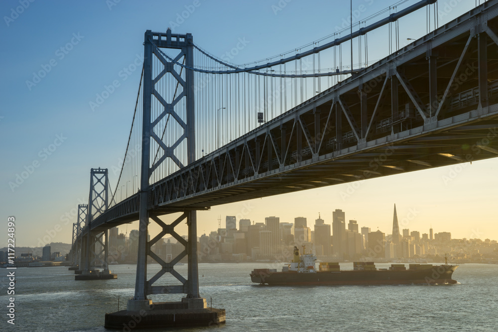 Fototapeta premium Container ship sails along San Francisco Bay at sunset