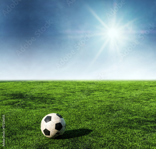 Soccer ball on green grass at soccer field with sunshine on blue sky © SasinParaksa