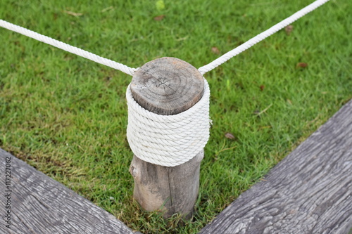 Closeup view of rope tied around wooden pillar at garden