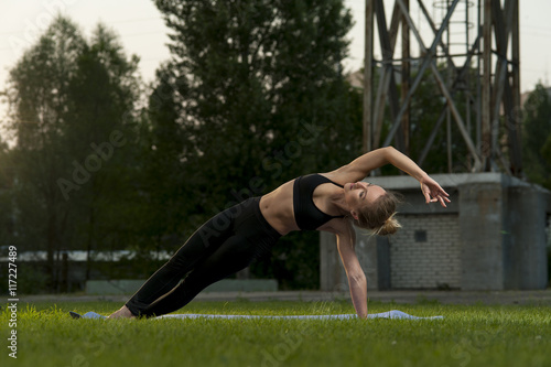 Yoga outdoors: fit woman in black sportswear practicing outdoors