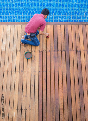 A man painting exterior wooden pool deck, Top view