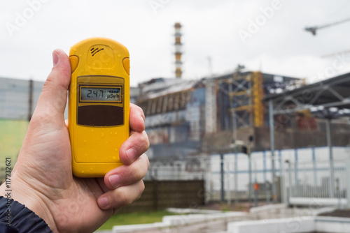 radiometer in hand with fourth Chernobyl reactor on the background