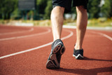 Legs of young sportsman running on stadium track
