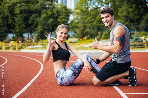 Young beautiful happy couple doing sports exercises at the stadium