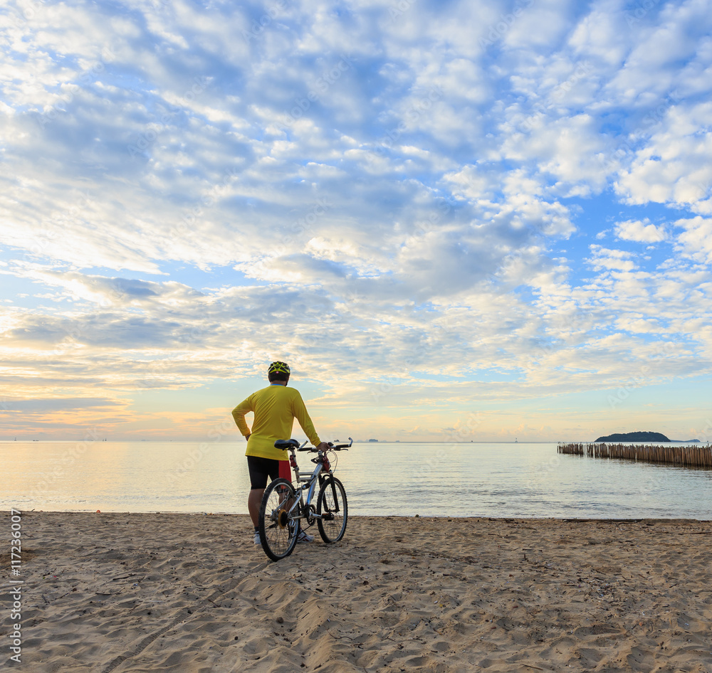 Fototapeta premium Cyclist with bicycle at the sunrise beach
