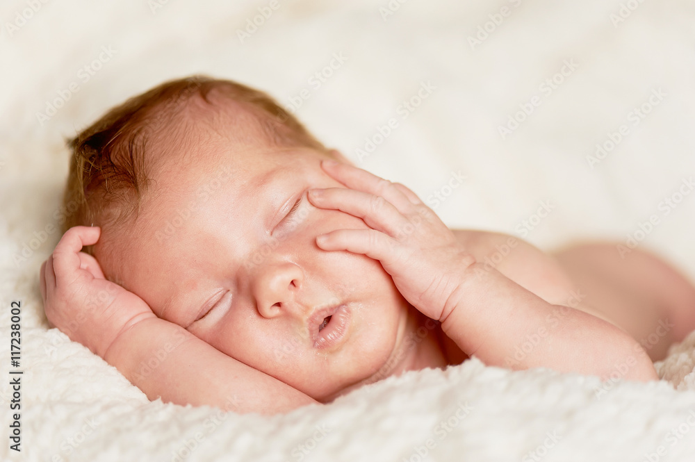 The baby, newly born, lies on the bright plaid and sleeping, handle the person The baby, newly born, lies on the bright plaid and sleeping, handle the person