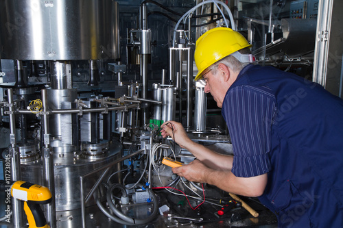 skilled worker while fixing a bottling plant during maintenance work