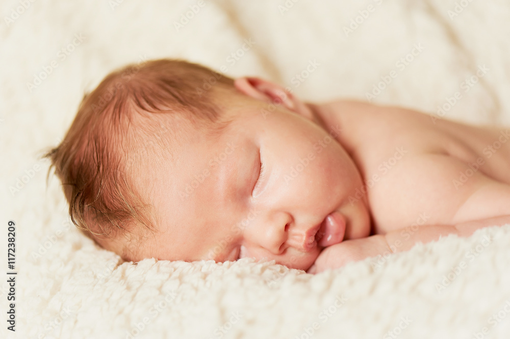 The baby, newly born, lies on the bright plaid and sleeping, handle the person The baby, newly born, lies on the bright plaid and sleeping, handle the person