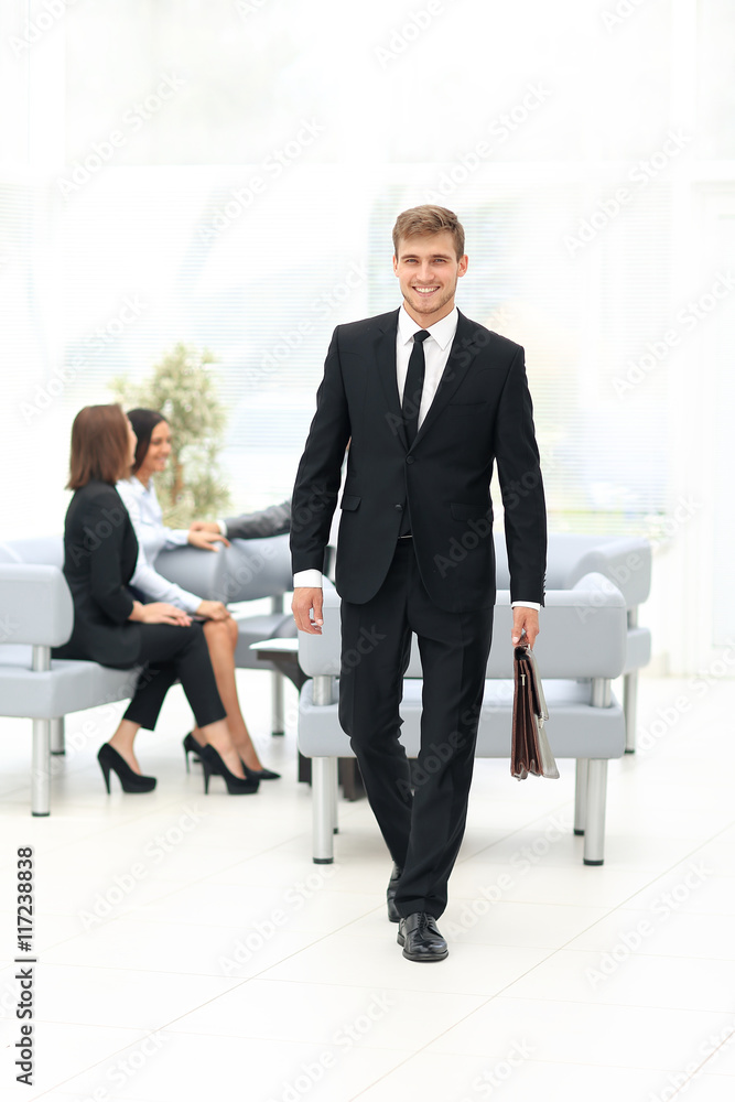 Handsome business man standing with his collegues in background Handsome business man standing with his collegues in background
