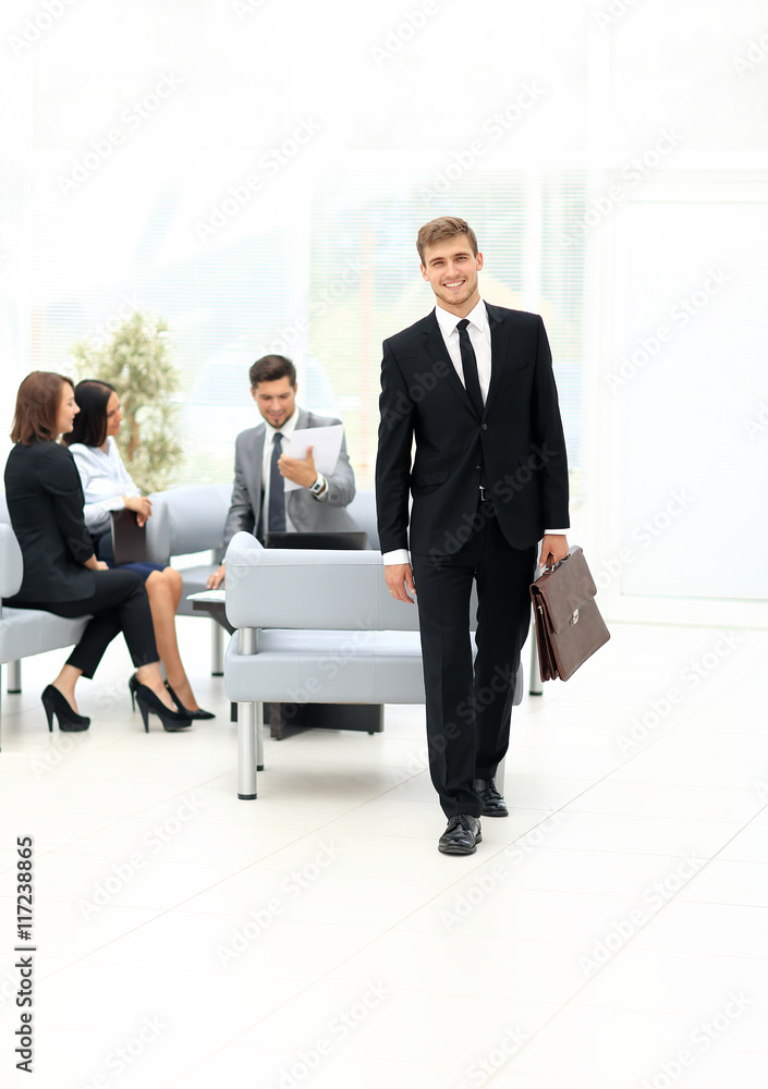 Successful business man standing with his staff in background at Successful business man standing with his staff in background at