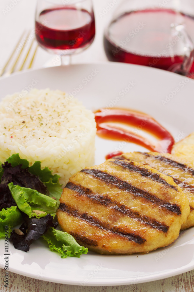 grilled hamburger with rice, salad and chips on plate with glass red wine grilled hamburger with rice, salad and chips on plate with glass red wine