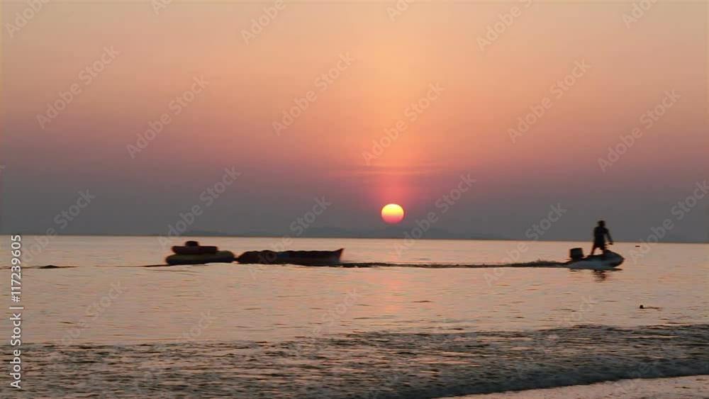 Sunset in the sea and silhouette of man hauling banana boat Sunset in the sea and silhouette of man hauling banana boat