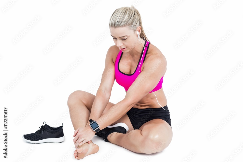 Injured female athlete sitting and touching ankle Injured female athlete sitting and touching ankle