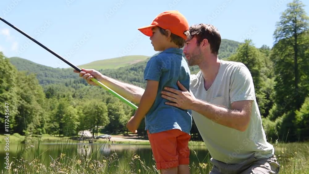 Father and son fishing together by mountain lake Father and son fishing together by mountain lake