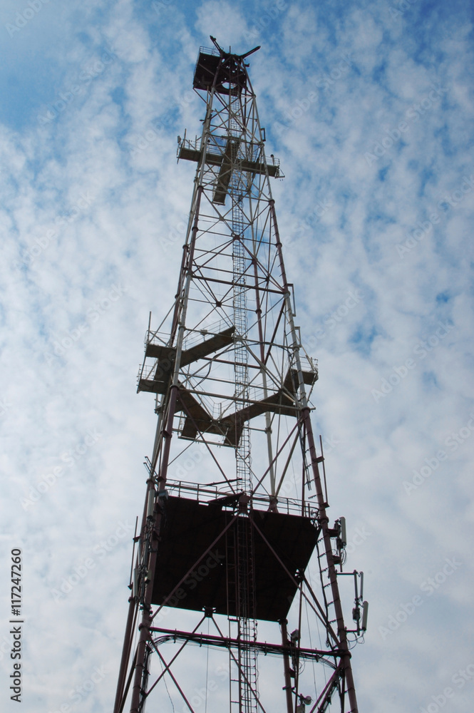 Telecommunications tower with blue cloudly sky transmitting the signal Telecommunications tower with blue cloudly sky transmitting the signal