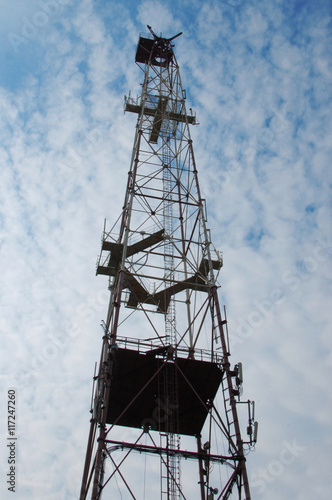 Telecommunications tower with blue cloudly sky transmitting the signal