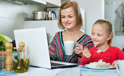 Smiling woman sitting in the kitchen with daughter