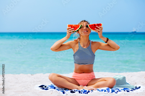 Woman eating watermelon on the beach