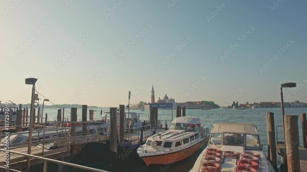 VENICE, ITALY - JUNE 19, 2016: Parking gandolas on the Doge's palace embankment with the bell tower of the Saint Giorgio Maggiore church view, Venice, Italy. VENICE, ITALY - JUNE 19, 2016: Parking gandolas on the Doge's palace embankment with the bell tower of the Saint Giorgio Maggiore church view, Venice, Italy.