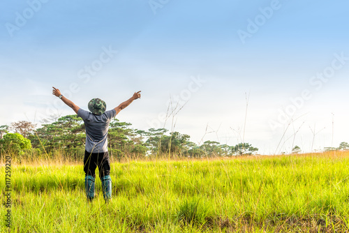 Young man in spreading hand in green meadow.