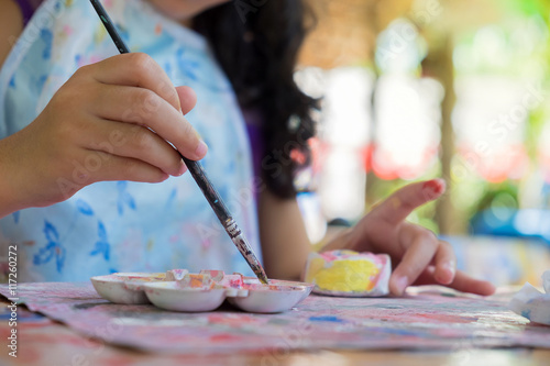Little hands of kid painting on the plaster soft focus.
