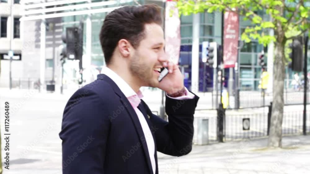 Business man in the city. He is formally dressed and is talking to someone on his smartphone.