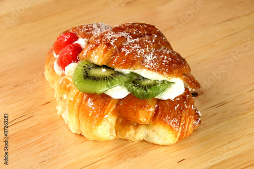 Filled croissant with whipped cream and fresf fruits. photo