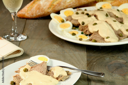 A dish of vitel tonné, fork, a glass of white wine and some bread. photo