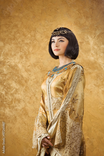 Beautiful woman like Egyptian Queen Cleopatra on golden background