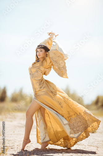 Beautiful woman like Egyptian Queen Cleopatra on in desert outdoor.