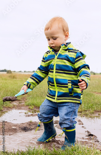 A little child is playing in a muddy puddle                                                            A little child is playing in a muddy puddle © yanapovhan