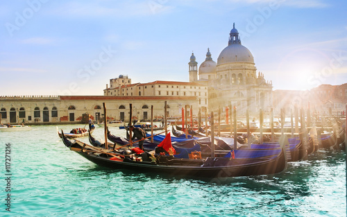Beautiful view of traditional Gondola on famous Canal Grande with Basilica di Santa Maria della Salute in golden evening light at sunset in Venice, Italy